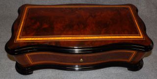 REUGE CYLINDER MUSIC BOX Reuge Inlaid Cylinder Music Box. Hand crafted in Switzerland. Works perfectly. Measures 5-1/4" tall x 15-3/4" wide x 8-1/2" deep. Condition is Excellent. Mint. No damage. Starting Bid $3,000. Auction Estimate $4,000 - $8,000.